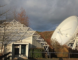Besucherpavillon am Radioteleskop Effelsberg. Der Aussichtspunkt unmittelbar vor dem Radioteleskop ist über einen kurzen Zickzackweg unterhalb des Geländers erreichbar. (Bild: Norbert Junkes/MPIfR (Nov. 2019))