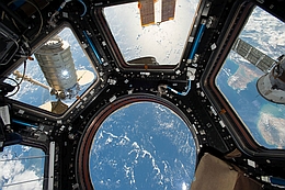 Cygnus OA-5 (links) am SSRMS von der Beobachtungskuppel der ISS Cupola aus gesehen (Bild: NASA)