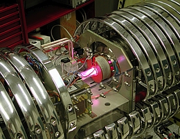 Ionenquelle des LUNA-Beschleunigers während einer Wartungsphase. Die Leuchterscheinung ist das Wasserstoffplasma, aus dem Wasserstoffkerne für die Fusionsreaktion gewonnen werden. (Bild: LUNA Collaboration/LNGS-INFN)
