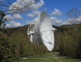 Das 100-m-Radioteleskop nahe Bad Münstereifel-Effelsberg, ca. 40 km südwestlich von Bonn. Das Foto zeigt das Teleskop vom Besucherpavillon aus. Ein kurzer Zickzackweg führt von dort aus zu einem Aussichtsplateau unmittelbar vor dem Teleskop selbst. (Bild: Norbert Junkes/MPIfR)