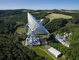 Das Radioteleskop in Effelsberg gehört zu den wichtigsten astronomischen Observatorien weltweit. Die Einbettung in ein malerisches Eifeltal sorgte Jahrzehnte für einen guten Schutz vor anthropogenen Funkaussendungen. Die vermehrte Nutzung von Breitbandkommunikation mittels großer Satellitenkonstellationen bereitet den Astronomen aber mehr und mehr Kopfzerbrechen, denn die Satelliten stehen überall auf der Erde hoch am Himmel. (Bild: Norbert Tacken / MPIfR)