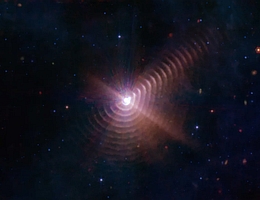 Die beiden Sterne in Wolf-Rayet 140 erzeugen alle acht Jahre ringförmige Staubschalen, wie auf diesem Bild des James-Webb-Weltraumteleskops zu sehen. Die Ringe entstanden jeweils bei der größten Annäherung beider Sterne. Dabei kollidieren die Sternwinde, wodurch das Gas komprimiert wird und zur Entstehung von Staub führt. (Bild: NASA, ESA, CSA, STScI, JPL-Caltech)