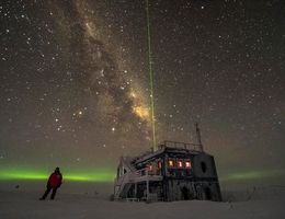 IceCube-Forscher vor der IceCube-Forschungsstation im antarktischen Winter, hier mit Polarlicht, Sternenhimmel und einem Lidar-Laserstrahl zu Vermessung der Atmosphäre. (Foto: Martin Wolf / IceCube/NSF)