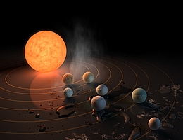 Diese künstlerische Darstellung zeigt das Planetensystem TRAPPIST-1 mit einem sehr kühlen roten Zwergstern in seinem Zentrum. Sieben Planeten von der Größe der Erde umkreisen ihn. Auf jedem dieser Planeten könnte es flüssiges Wasser geben. Planeten, die weiter vom Stern entfernt sind, weisen wahrscheinlich größere Mengen an Eis auf, insbesondere auf der dem Stern abgewandten Seite. Die Größen und Entfernungen sind nicht maßstabsgetreu. (Herkunftsnachweis: NASA/JPL-Caltech/R. Hurt (IPAC))