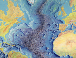 Eine farbige Weltkarte, die alle Gebirge und Gräben in den Ozeanen dunkel schattiert hervortreten lässt. Das Grabenbruchsystem, das die ganze Welt umspannt.