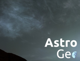 Düstere Landschaft: Ein Bergrücken, der dunkel, aber leicht rötlich erscheint, darüber ein grauer Himmel mit diffusen Wolkenformationen.