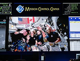 6. April 2026 – Die Besatzung von Artemis II – Jeremy Hansen der CSA (ganz links) sowie die NASA-Astronauten Christina Koch (Mitte links), Reid Wiseman (Mitte rechts) und Victor Glover (rechts) – sind auf den Bildschirmen des White Flight Control Room im Mission Control Center der NASA im Johnson Space Center der Behörde in Houston zu sehen. Bildnachweis: NASA/Robert Markowitz
