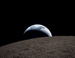 Erduntergang Eine in gedämpftem Blau gehaltene Erde mit strahlend weißen Wolken versinkt hinter der kraterübersäten Mondoberfläche. Auf dem dunklen Teil der Erde herrscht Nacht. Auf der Tagseite der Erde sind wirbelnde Wolken über der Region Australien und Ozeanien zu sehen. Im Vordergrund weist der Ohm-Krater terrassierte Ränder und einen flachen Boden auf, der von zentralen Erhebungen unterbrochen wird. Zentrale Erhebungen bilden sich in komplexen Kratern, wenn die bei einem Einschlag verflüssigte Mondoberfläche während der Kraterbildung nach oben spritzt. Bildquelle: NASA